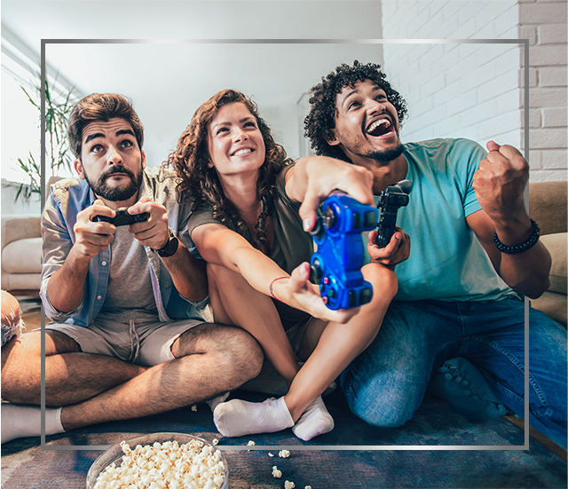 Group of young smiling people sitting on floor and playing video games, happy after Canesten fungal skin infection treatment